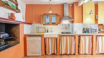 A kitchen with a dishwasher, stove, microwave, and striped curtains.