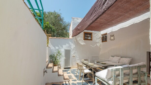 Une petite pièce agréable, avec un sol en pierre, un lit, une table avec des chaises et une fenêtre.