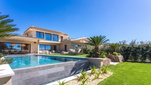 Une maison moderne dotée d’une piscine, d’un espace extérieur aménagé et d’une pelouse bien entretenue.
