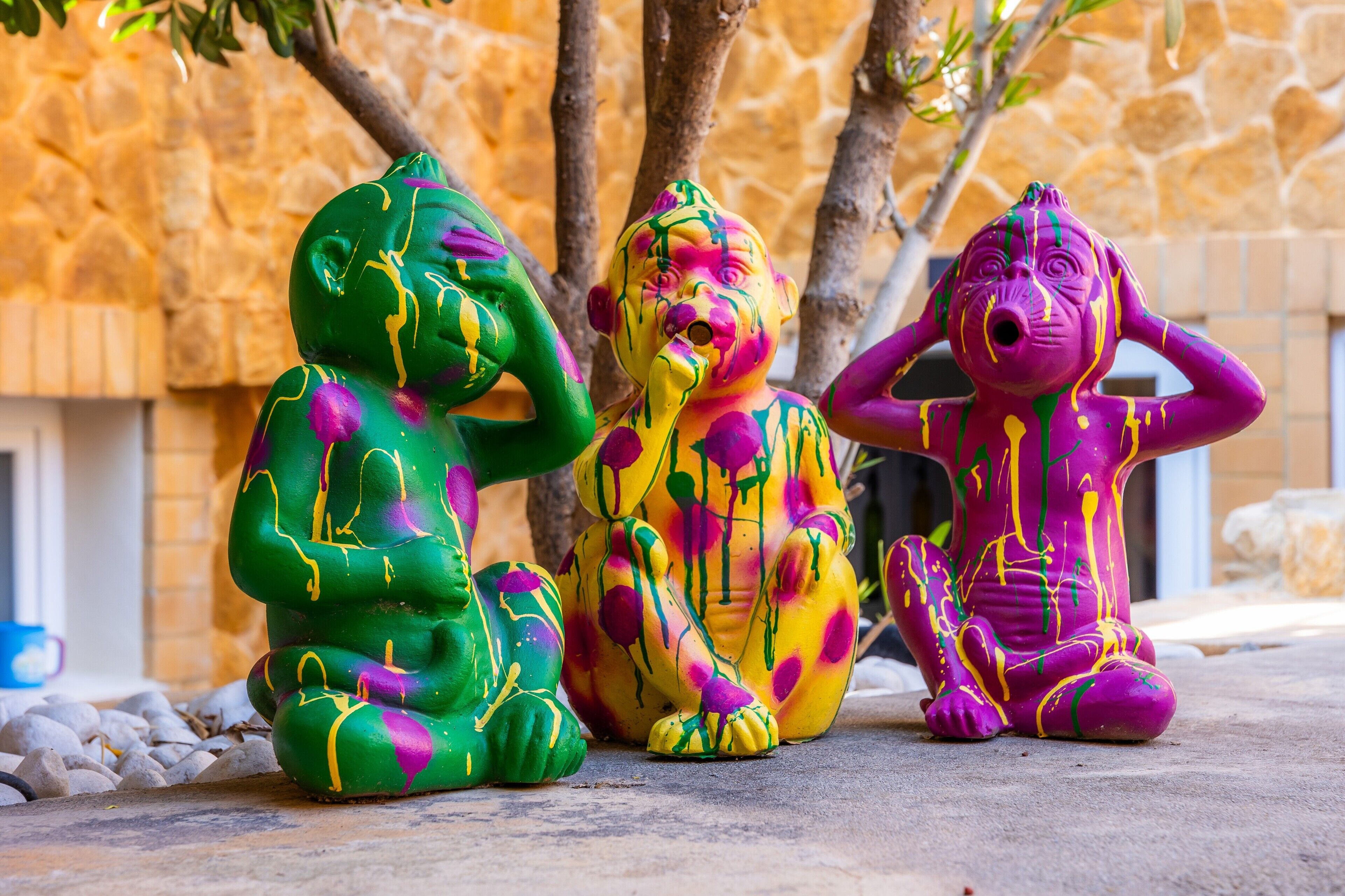 Three colorful statues of elephants sitting on a stone surface.