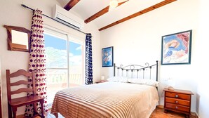 Quarto com cama, cadeira de madeira, cômoda e obras de arte nas paredes.