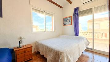 Une chambre à coucher avec un lit, une commode, une lampe, un tableau et une fenêtre donnant sur un beau paysage.