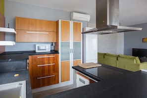 Une cuisine moderne avec des meubles en bois, un four à micro-ondes encastré et un plan de travail noir.