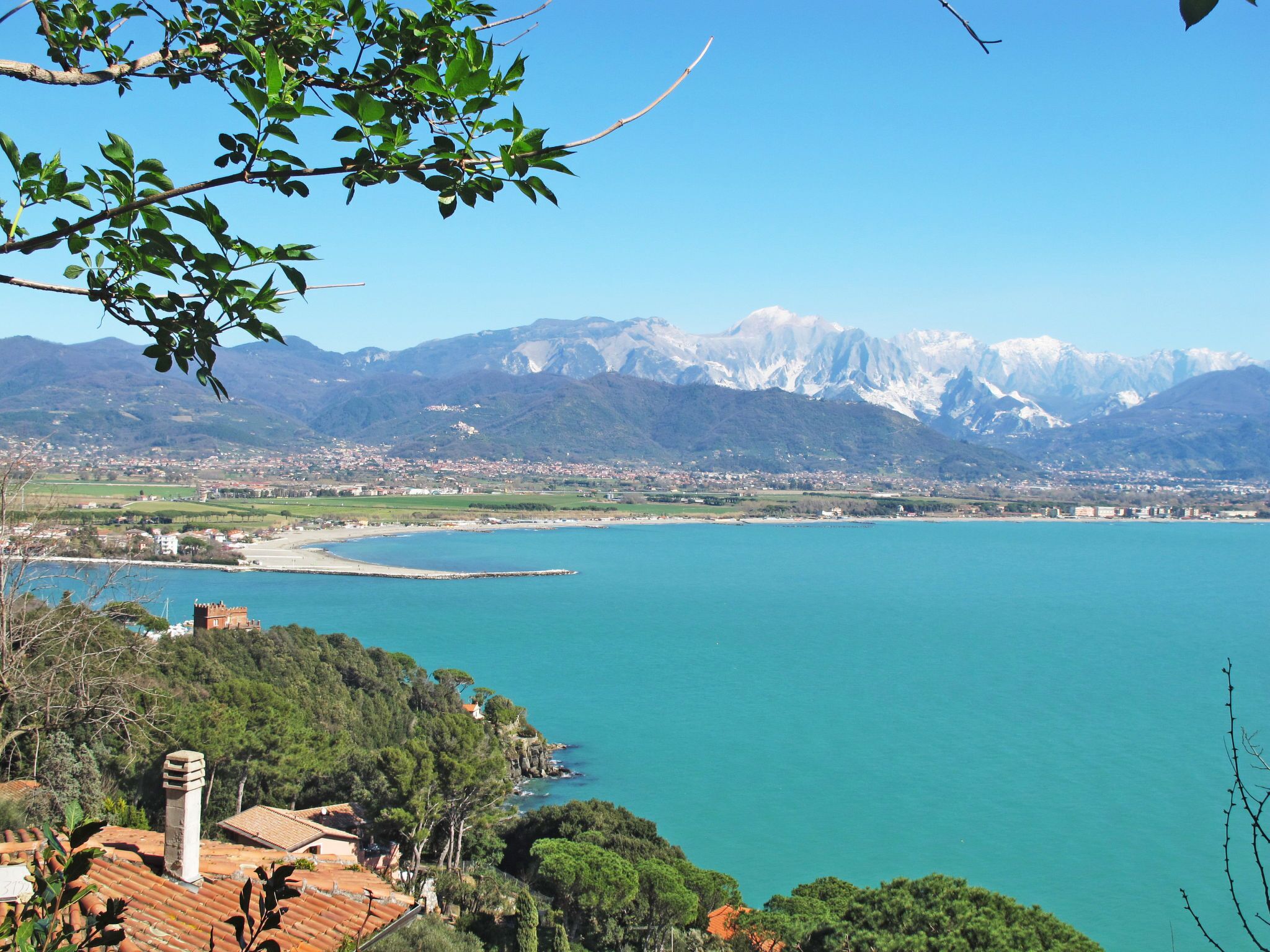 Eine Küstenstadt mit Bergblick, blauem Himmel und Blick auf das Meer.