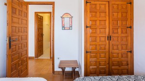 Een kamer met een houten deur, een klein tafeltje en een spiegel aan de muur.
