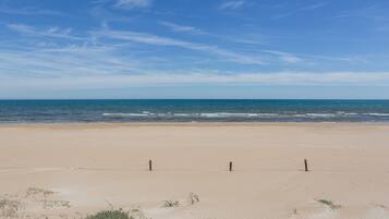 Ein Strand mit einem Zaun, blauem Himmel und dem Meer.