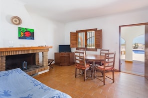 A living room with a fireplace, dining table, chairs, and a TV.