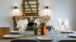 Une table à manger dressée avec des assiettes, des verres et un vase rempli de fleurs.