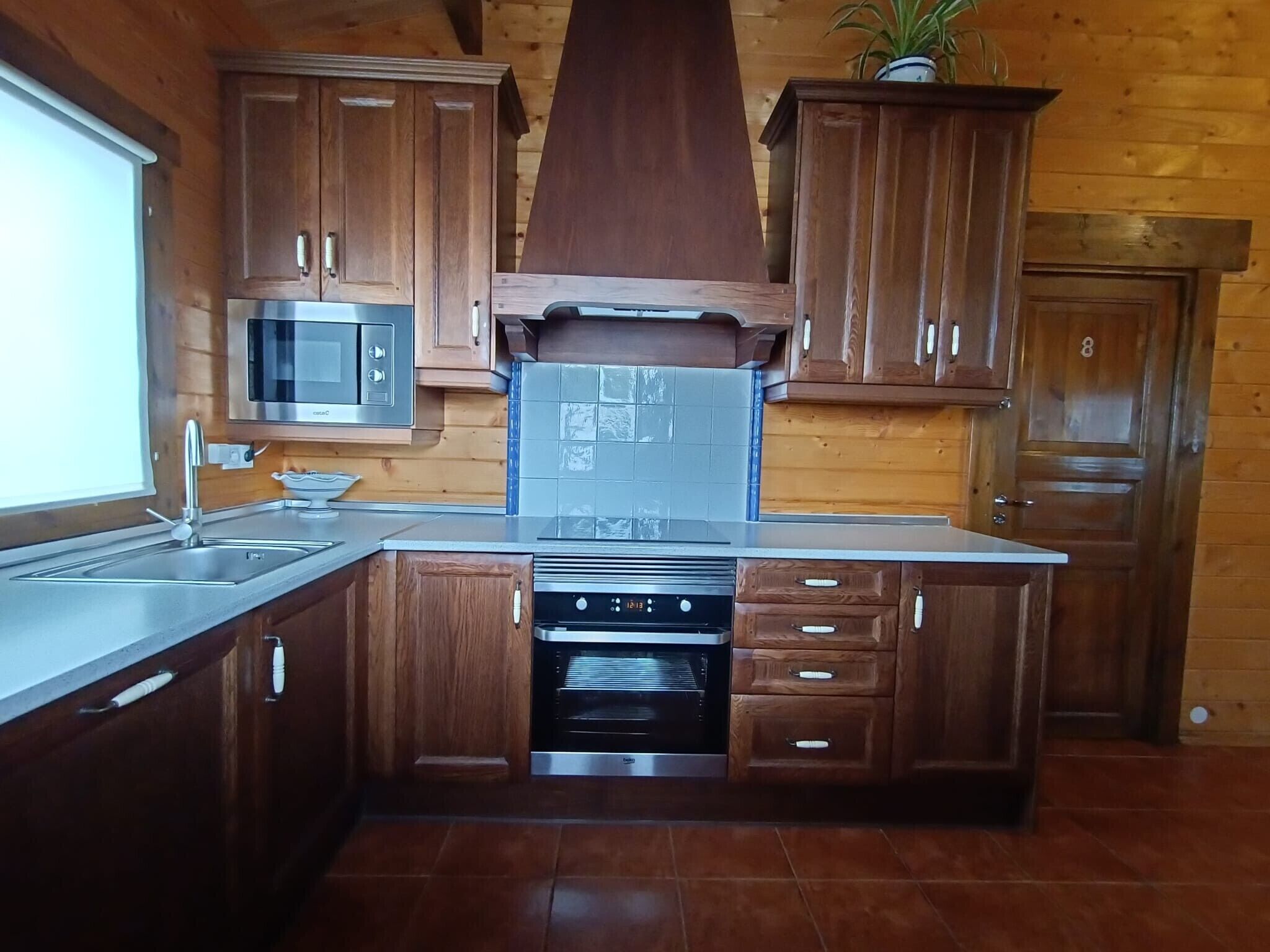 A kitchen with wooden cabinets, a stainless steel microwave, a built-in oven, and a sink.