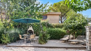 Un pati amb taula i cadires, una barbacoa i una zona de relaxació amb seients.