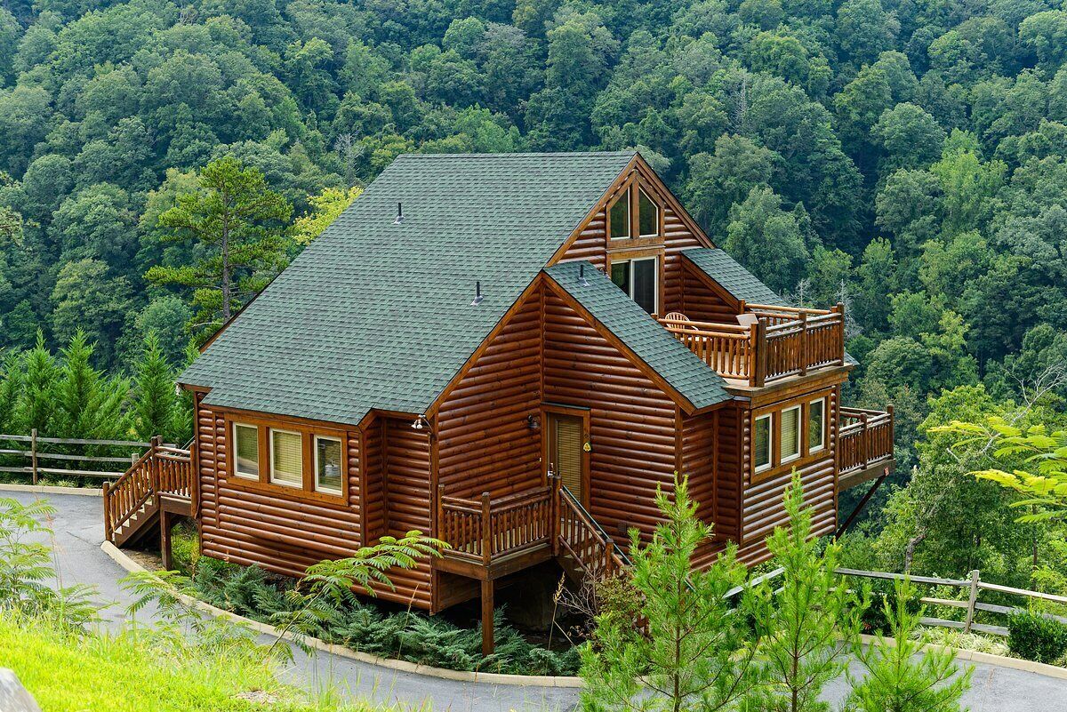A log cabin with a steep roof, a balcony, and a porch.