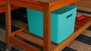 A room with a wooden table, turquoise storage baskets, a teal sofa, and a starfish-patterned pillow.