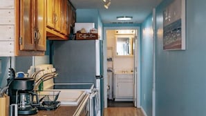 A kitchen with wooden cabinets, a coffee bar, a refrigerator, and a microwave.