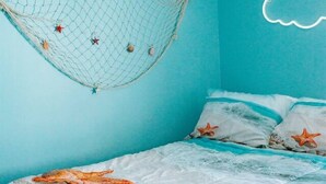 A bedroom with a bed, a hanging net, and a cloud-shaped light fixture.
