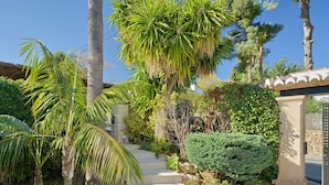 A landscaped garden with palm trees, a stone wall, and a well-maintained hedge. - La Terraza del Sol by Interhome (Jávea)
