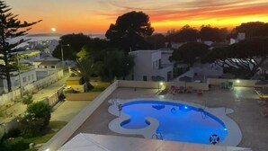 Ein Schwimmbecken mit einem außergewöhnlichen Design, umgeben von Gebäuden und Bäumen, im Abendlicht.