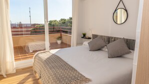 Ein Schlafzimmer mit einem großen Bett, einem Balkon mit Geländer, einer Topfpflanze und einem wandmontierten Spiegel.