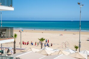 A beach with people, umbrellas, and a clear sky.