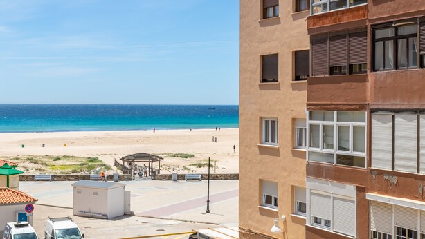 Un edificio costero con varias ventanas, vista a la playa y cielo despejado.