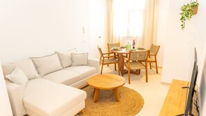 Una sala moderna con sofá, una mesa de centro y una mesa de comedor con sillas.