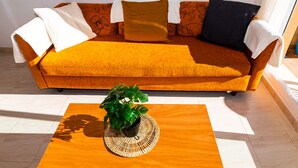 A room with a sofa, a coffee table, and a potted plant. - Apartamento Sereno 5 | Piscina, Garaje, Terraza y Playa (Los Caños de Meca)