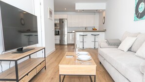 A modern living room with a flat-screen TV, wooden coffee table, and a light-colored sofa. - Casa Los Hierros | Reformada Cerca Playa (Barbate)
