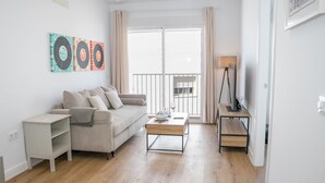 A living room with a sofa, coffee table, and artwork on the wall. - Casa Los Hierros | Reformada Cerca Playa (Barbate)