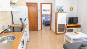 Een knus verblijf met een kitchenette, een eethoek, een televisie en een bed op de achtergrond.