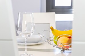 A dining table with a wine glass, a white plate, and a fruit basket. - Apartamento Vistas de Rajamanta | +Terraza, Playa + Garaje (Barbate)