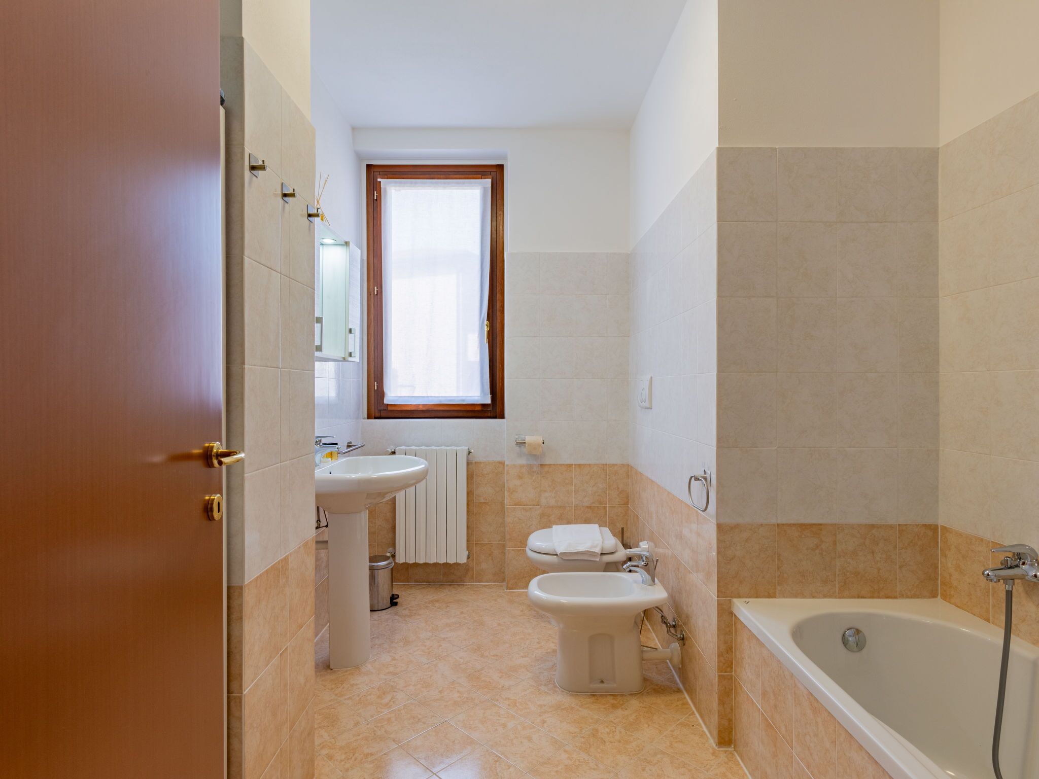 A bathroom with a sink, toilet, bidet, and bathtub.