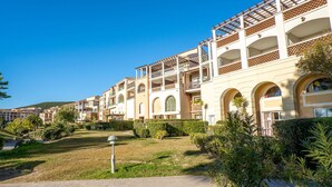 A multi-story hotel with balconies, a landscaped garden, and a clear blue sky. - L'Esquinade (F4 218) by Interhome (Agay Village Cap Esterel)