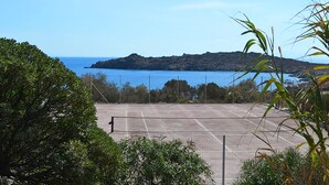 Una pista de tennis amb vista al mar i una illa a la distància.