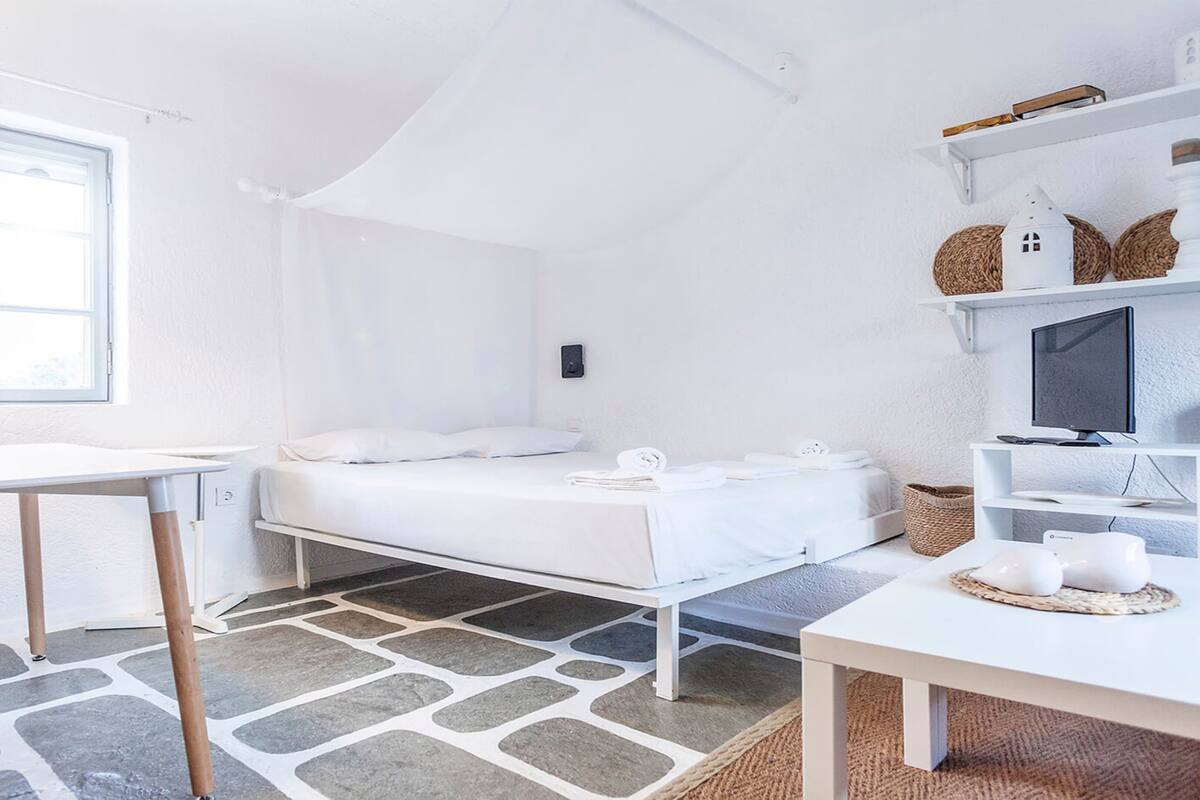 Una habitación moderna y minimalista con una cama, un escritorio y un televisor.