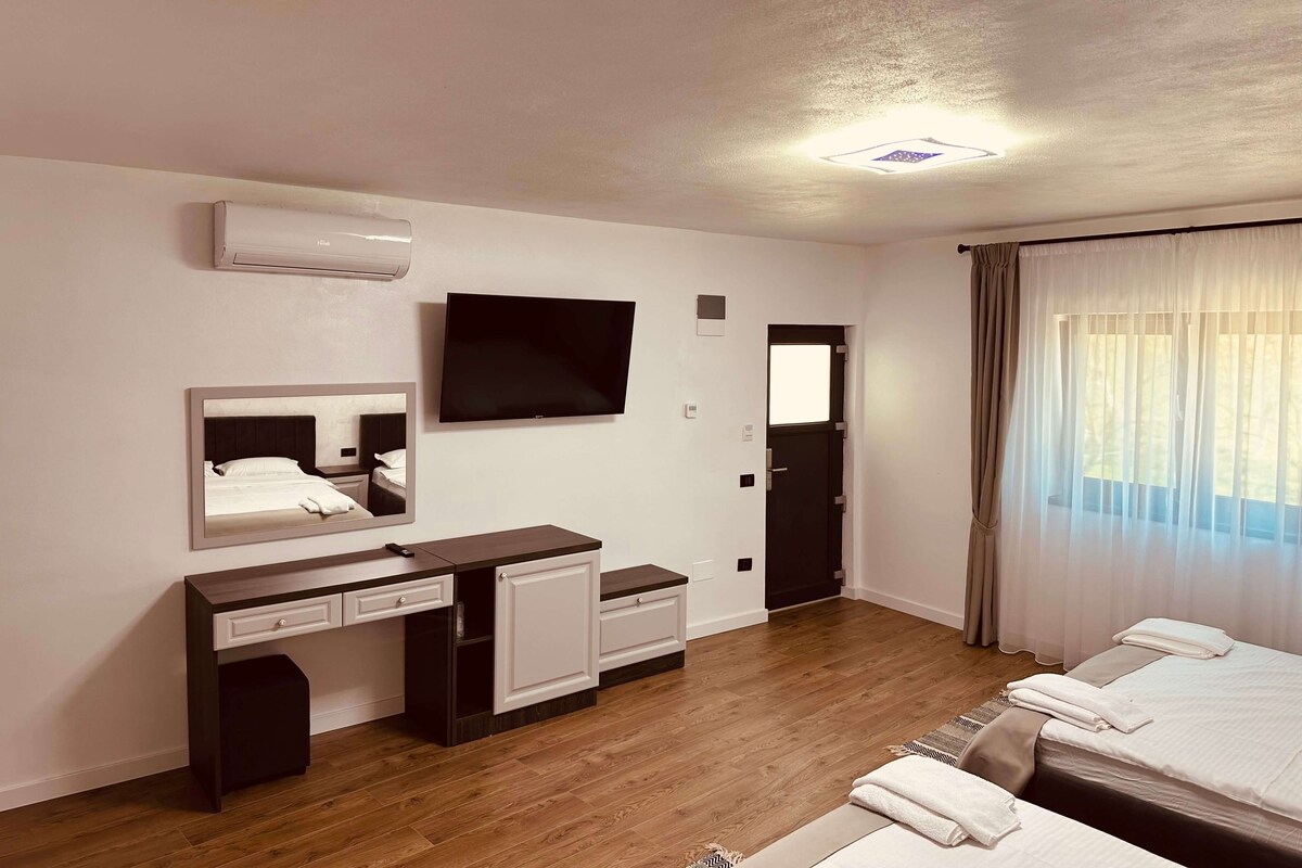 Una habitación de hotel con una cama, un escritorio con una silla, un televisor y una ventana con cortinas.