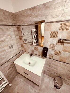 Un baño con un lavabo grande, toallero, espejo y retrete.