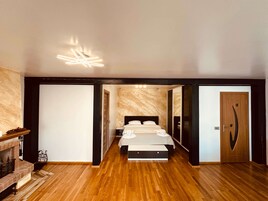 Un dormitorio moderno con una cama grande, una chimenea y una pared de mármol.
