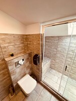 Un baño moderno con ducha, inodoro y secamanos.