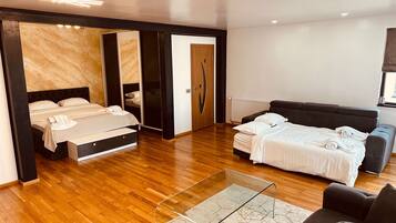 Een moderne slaapkamer met een groot bed, een kleiner bed, een bank en een glazen salontafel.