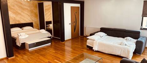 A modern bedroom with a bed, a sofa, a glass coffee table, and a wardrobe.