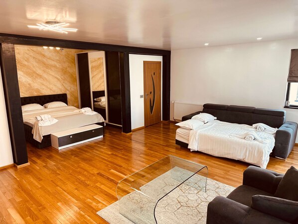 A modern bedroom with a bed, a sofa, a glass coffee table, and a wardrobe.