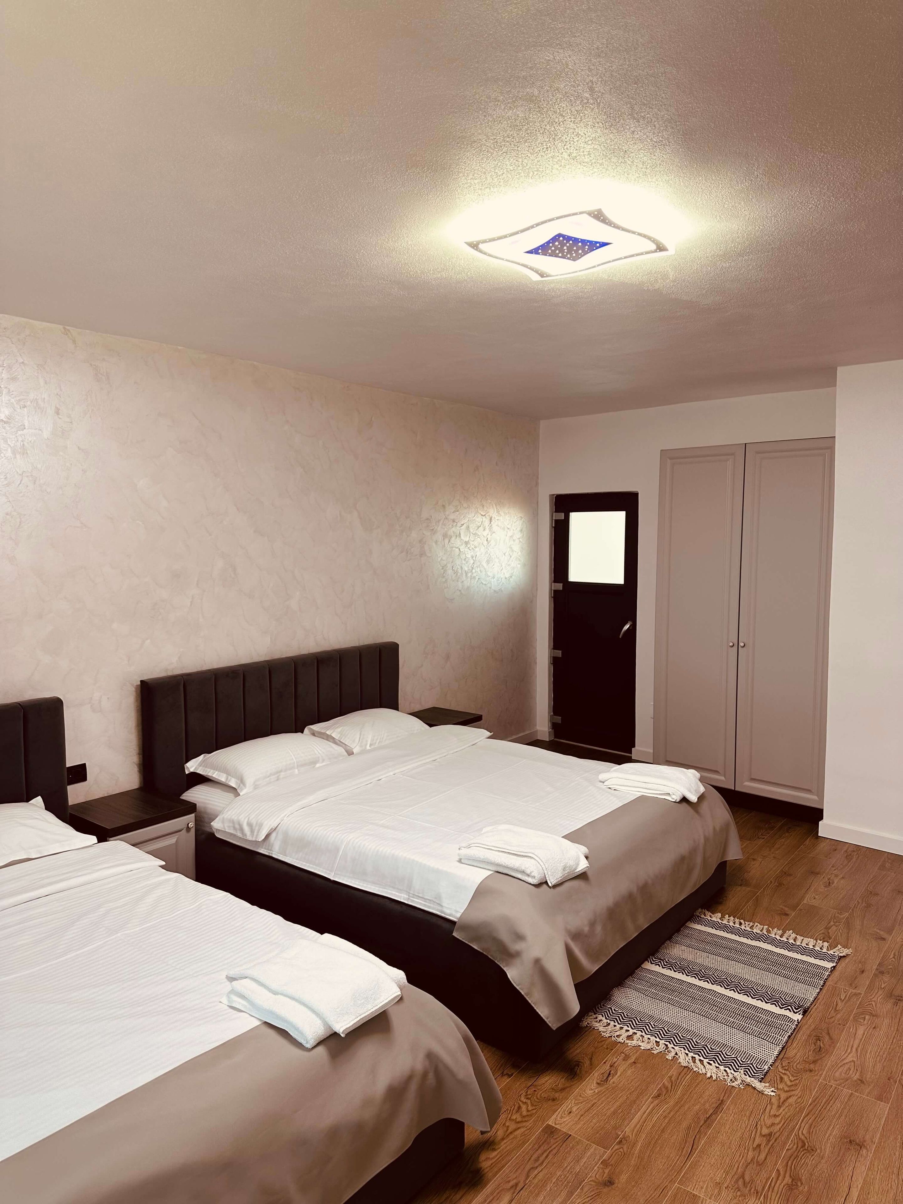 A hotel room with two beds, a wardrobe, and a small table.