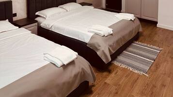 A hotel room with two beds, a wardrobe, and a small table.