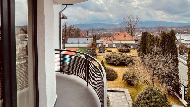 A balcony with a view of a residential area, including houses and trees. - Casa Yda (Horezu)