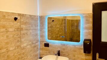Een moderne badkamer met een grote spiegel, een wastafel en een handdesinfecterend middel.