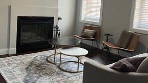 Ein Wohnzimmer mit Kamin, Deckenventilator und großem Teppich.