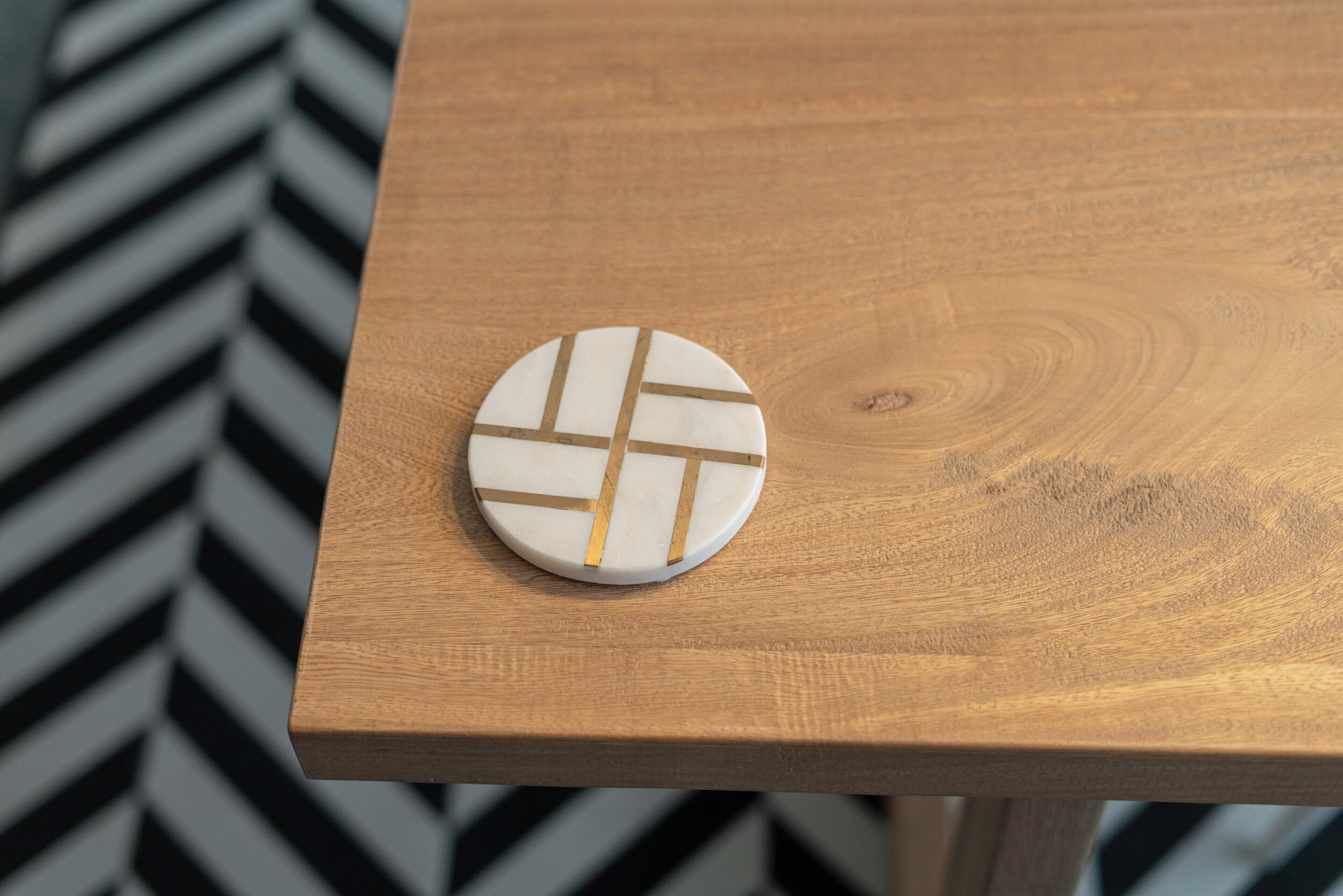 Un objeto redondo y blanco con líneas doradas sobre una mesa de madera.