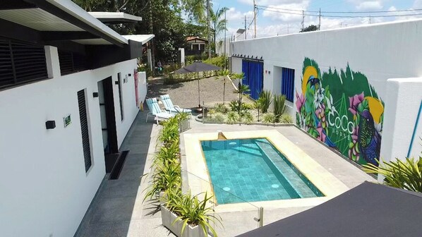 A pool area with a mural, a small pool, and lounge chairs.