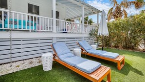 A covered outdoor area with two wooden lounge chairs and a white railing. - Big Mama`s Beach House! Available limited time only! 5 BDRs, POOL (Tybee Island)