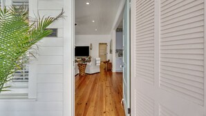 A hallway with wooden flooring, a television, and a dining area with a table and chairs. - Big Mama`s Beach House! Available limited time only! 5 BDRs, POOL (Tybee Island)