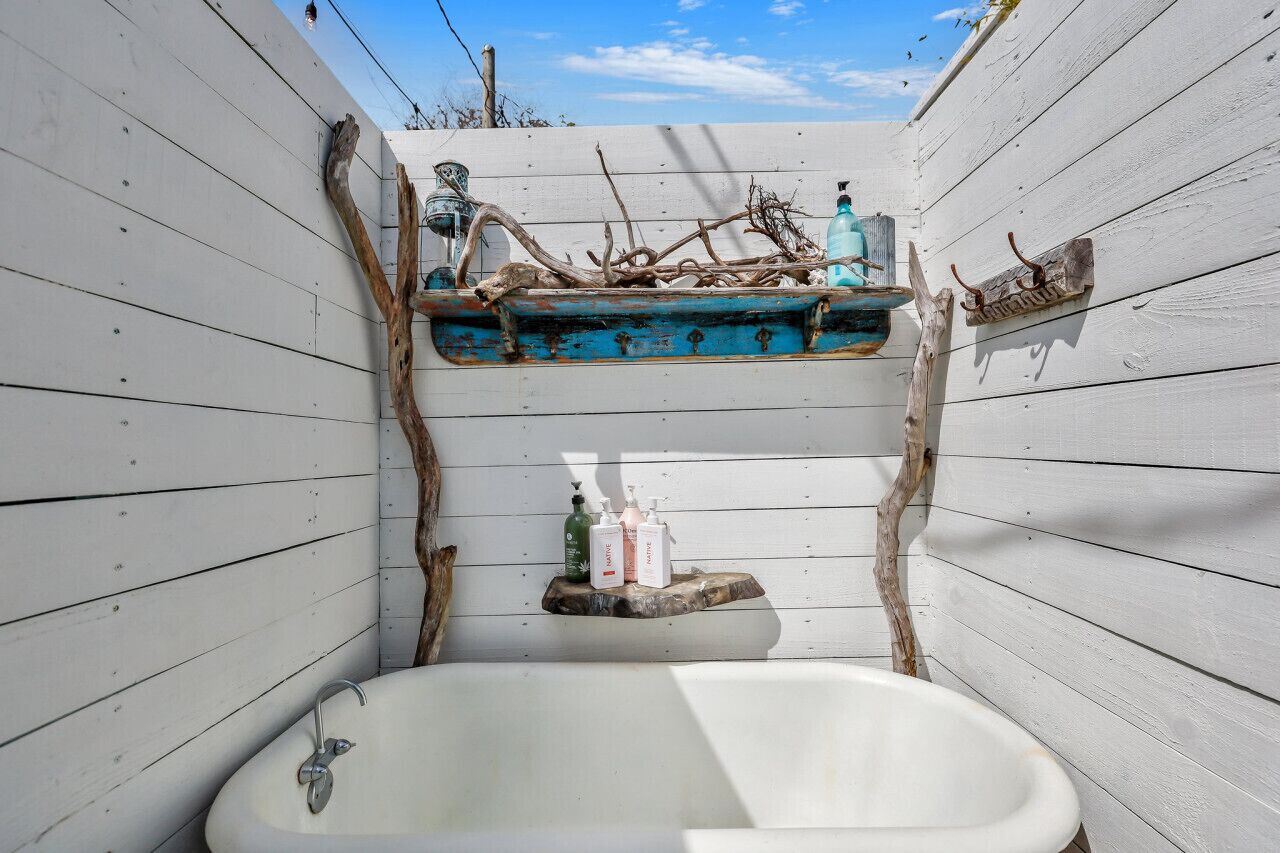 A bathroom with a white bathtub, wooden walls, and a shelf with toiletries.